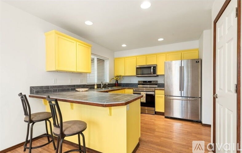 A kitchen with yellow cabinets and a stainless steel refrigerator.