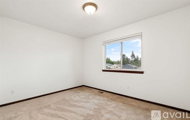 A room with a window showing a view of trees and houses outside.