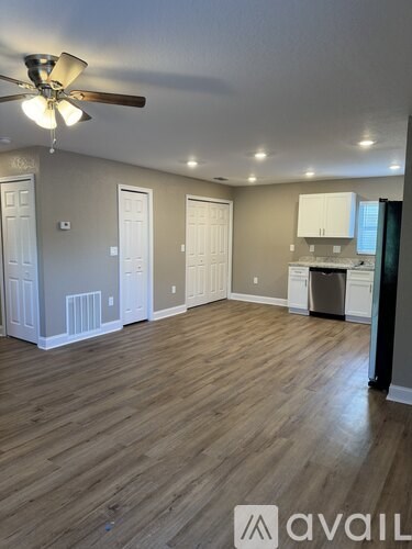 A room with a ceiling fan and wooden flooring.