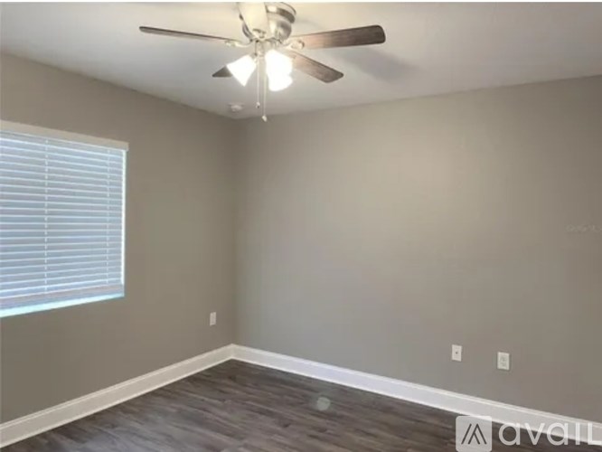 A room with a ceiling fan and a window with blinds.
