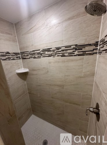 A shower area with a tiled wall and a shower head.