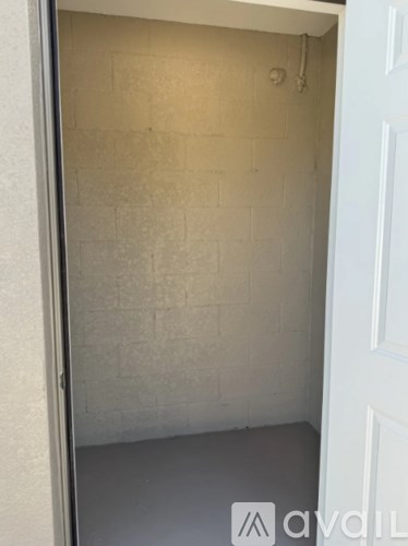 A white door is open to a small, empty room with a tiled wall.
