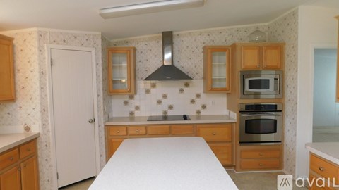 A kitchen with wooden cabinets and a white table.