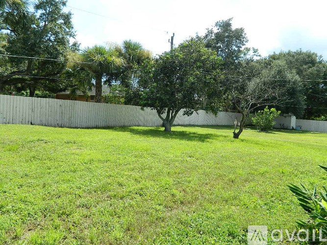 A grassy field with a fence and trees in the background.