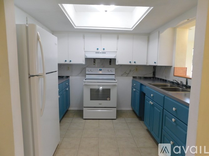 A kitchen with white cabinets and a white refrigerator.