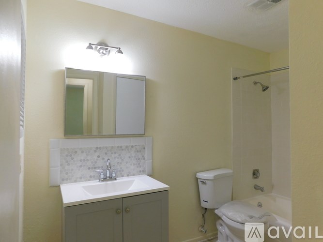 A bathroom with a sink, mirror, toilet and bathtub.