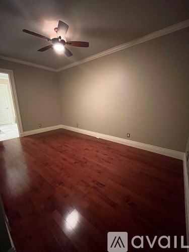 A room with a ceiling fan and wooden flooring.