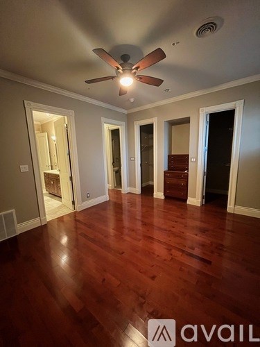 A room with a ceiling fan and wooden floors.