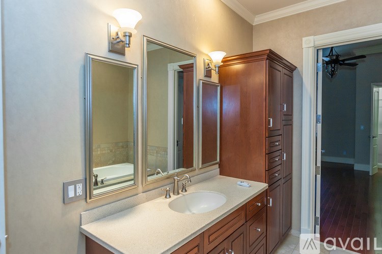 A bathroom with a sink, mirror, and cabinets.
