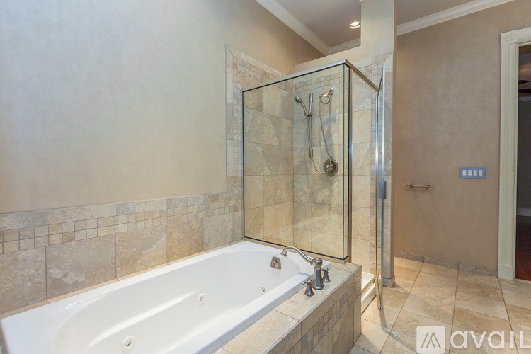 A bathroom with a white bathtub and a glass shower enclosure.
