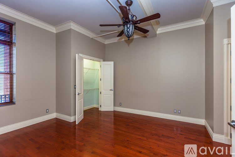 A room with a ceiling fan and wood flooring.