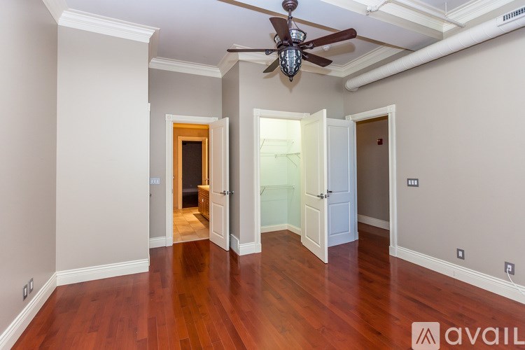 A spacious room with a ceiling fan and wooden floors.