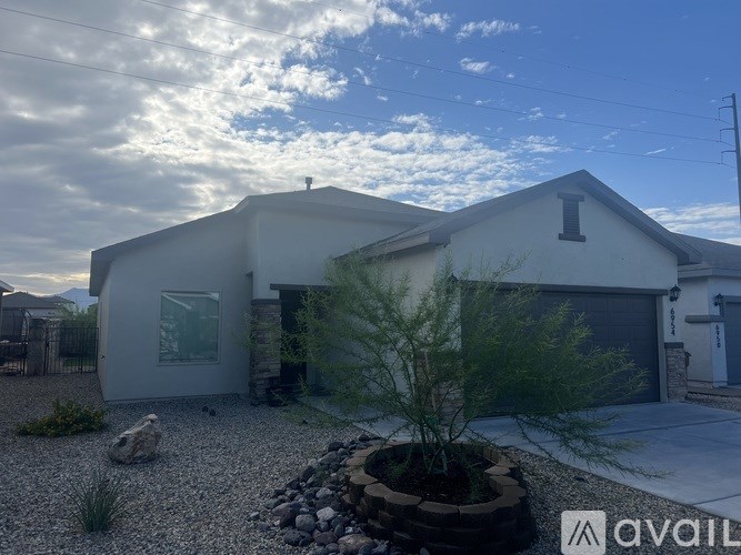 A modern house with a gravel driveway and a small tree in a planter.
