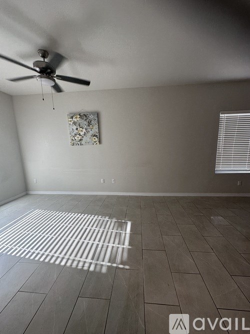 A room with a ceiling fan and a window with blinds.