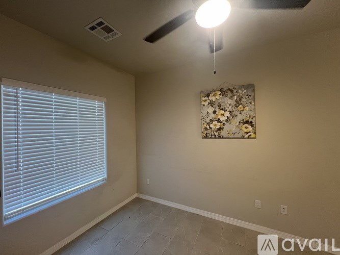 A room with a ceiling fan and a floral picture on the wall.