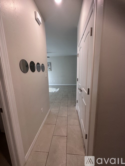 A hallway with a white door and a wall with circular mirrors.