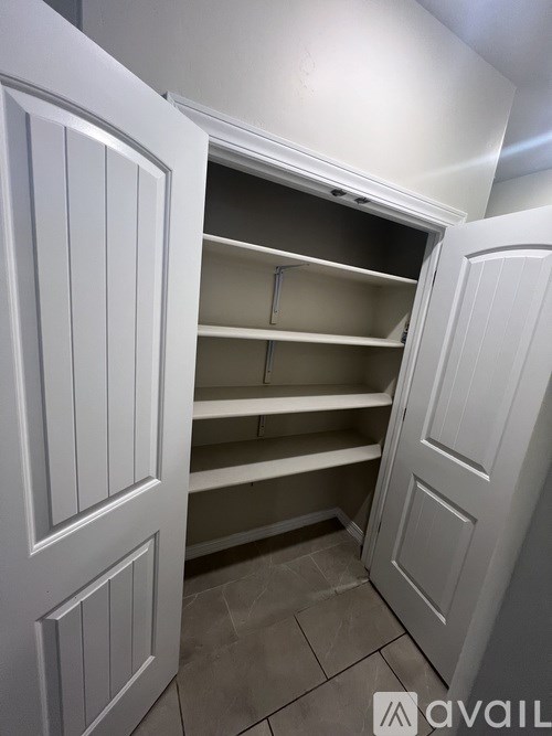 A white pantry with an open door and shelves.