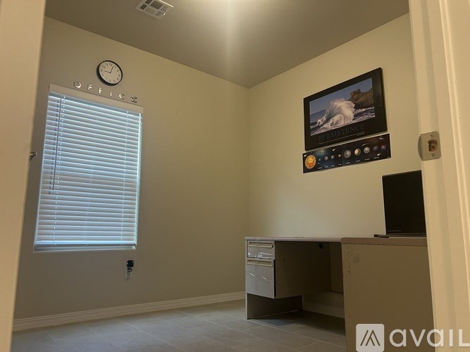 A wall clock in a room with a window and a desk.