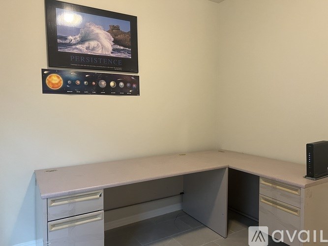 A white desk with a Persistence picture on the wall.