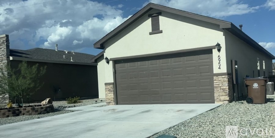 A house with a grey garage door and a brown trash bin.
