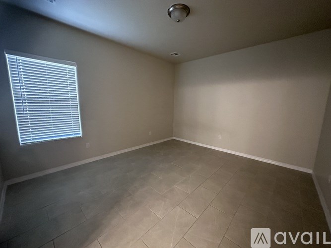 A room with tiled flooring and a window with blinds.