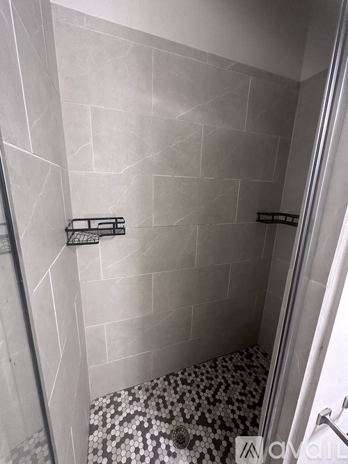 A bathroom with a tiled shower and a black and white tiled floor.