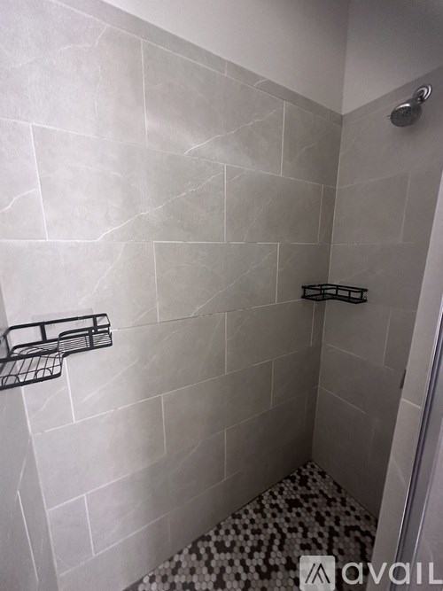 A bathroom with a shower and a black and white tiled floor.