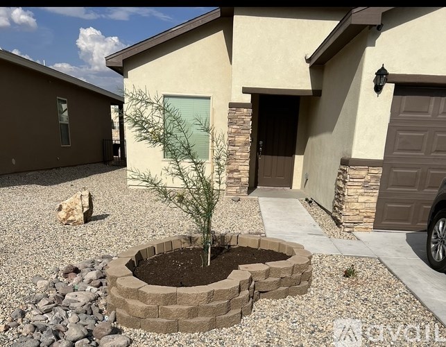 A small tree is planted in a circular brick planter in front of a house.