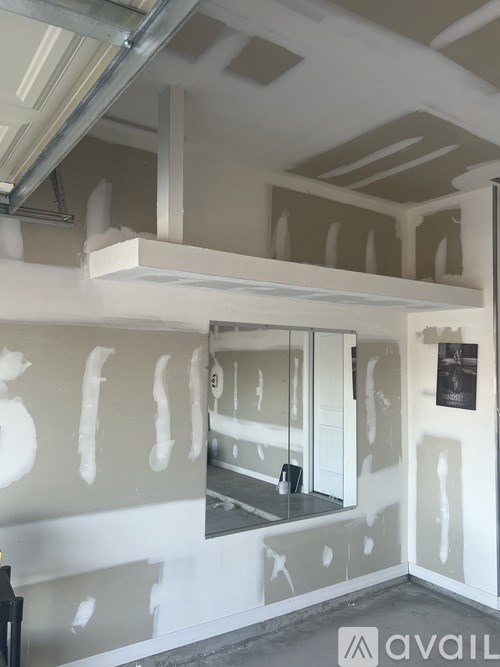 A room under construction with exposed beams and drywall.