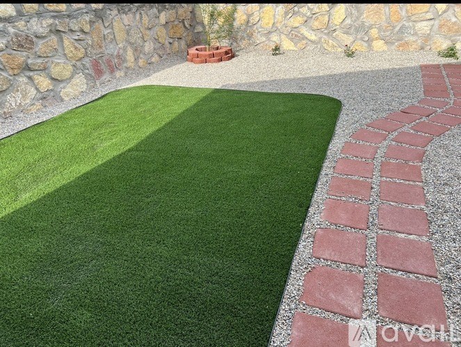 A stone wall with a red brick border and a green lawn.