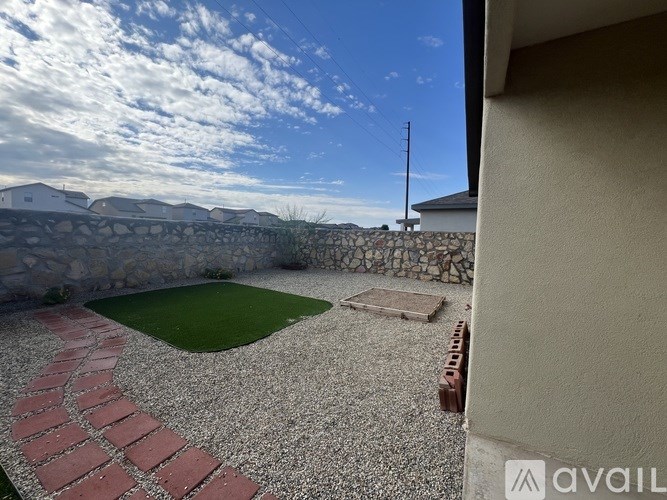 A backyard with a gravel area and a small grassy area.