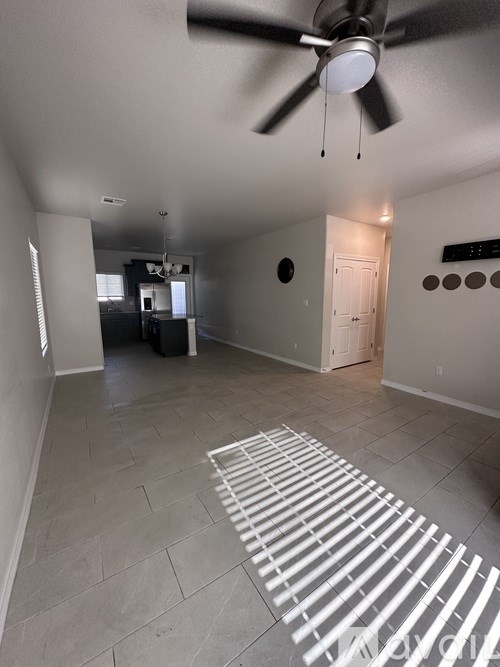 A room with a ceiling fan and a white rug on the floor.