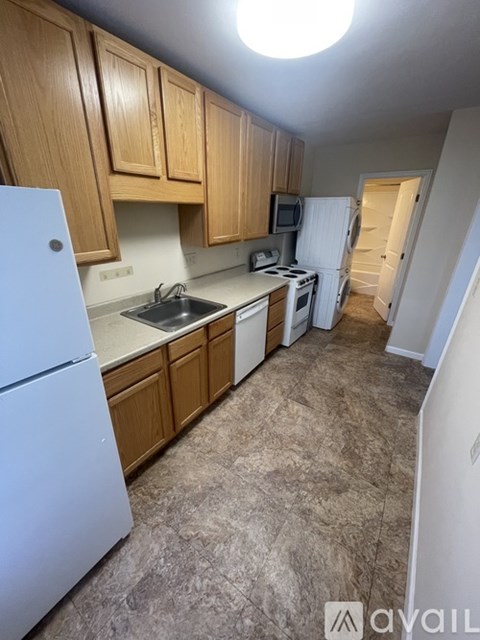 A kitchen with a white refrigerator and wooden cabinets.