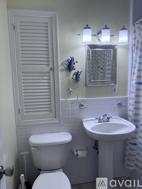 A white toilet sits next to a white sink in a bathroom.