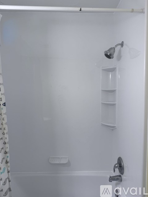 A white bathroom with a shower and a shelf.