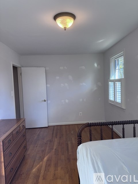 A bedroom with a bed, dresser, and window.