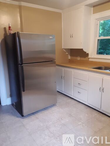 A black refrigerator in a kitchen with white cabinets.