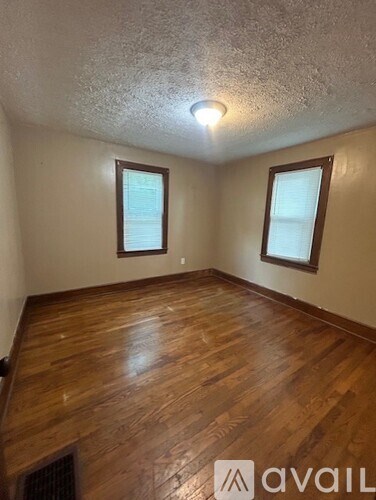 A room with wooden floors and two windows.