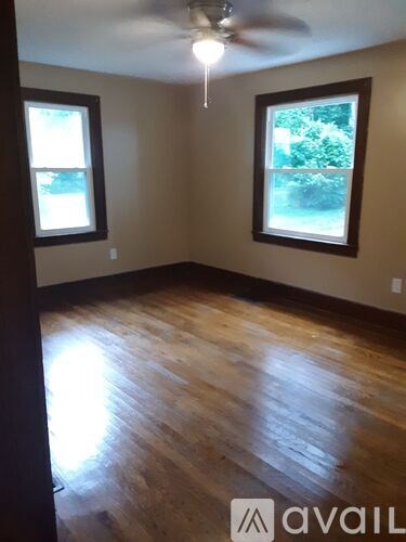 A room with wooden floors and two windows.