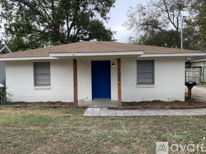 A white house with a blue door and a brown roof.