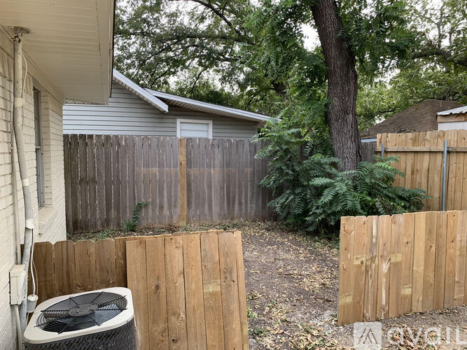 A backyard with a wooden fence and a tree.
