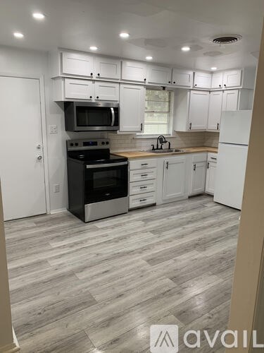 A kitchen with white cabinets and a wooden floor.