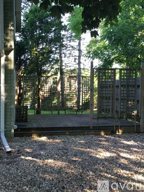 A wooden gate is in the middle of a gravel area.