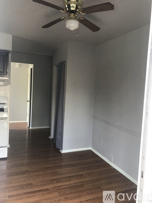 A room with a ceiling fan and wooden floors.