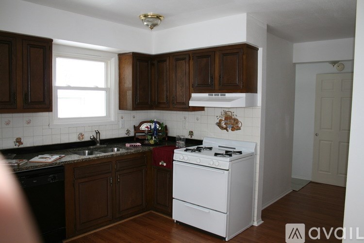 A kitchen with dark wood cabinets and a white stove top oven.