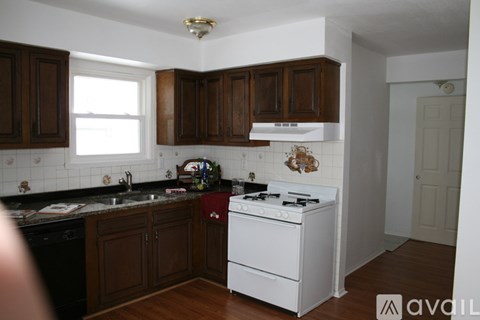 A kitchen with dark wood cabinets and a white stove top oven.