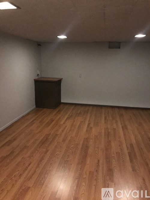 A room with wooden flooring and a brown cabinet.