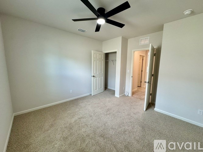 A room with a ceiling fan and carpeted floor.