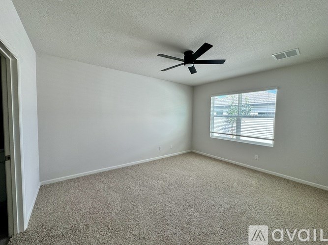A room with a ceiling fan and a window with blinds.