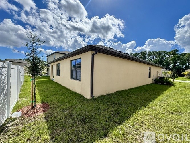 A beige house with a black roof and a white fence.